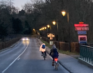 Usagers circulant à vélo ou en voiture sous un éclairage public vétuste